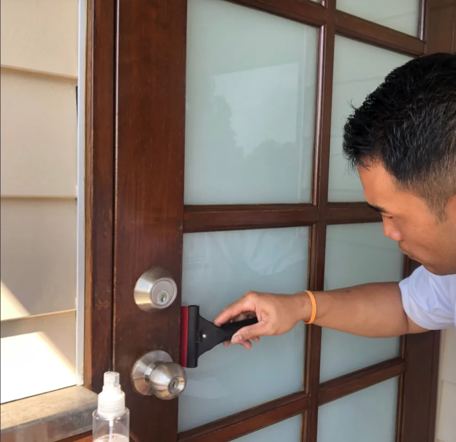 Jordan cleaning the glass panel of a timber front door