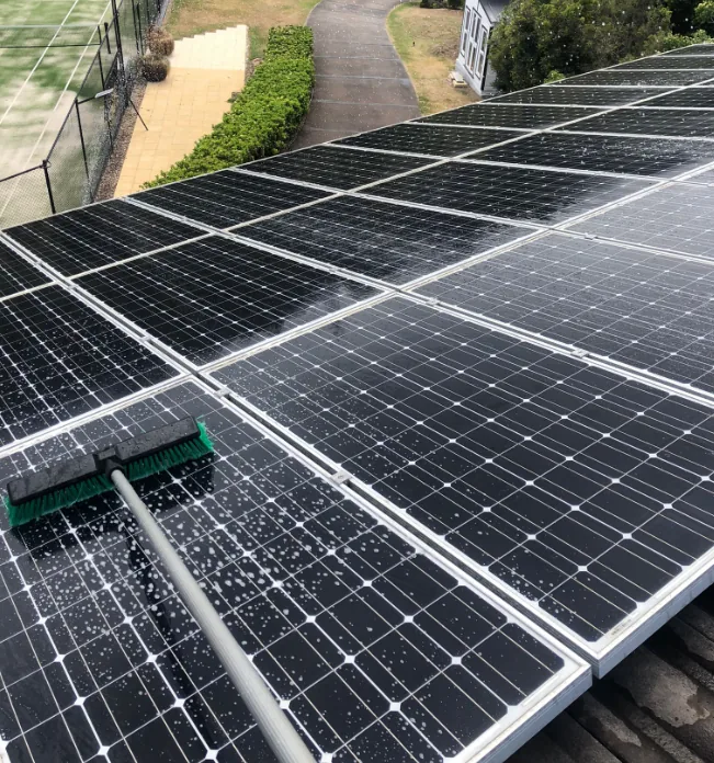 A soft brush and suds being worked across a rooftop solar array
