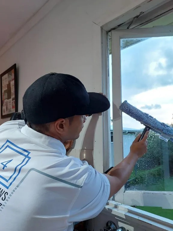 Jordan cleaning a large window with a squeegee